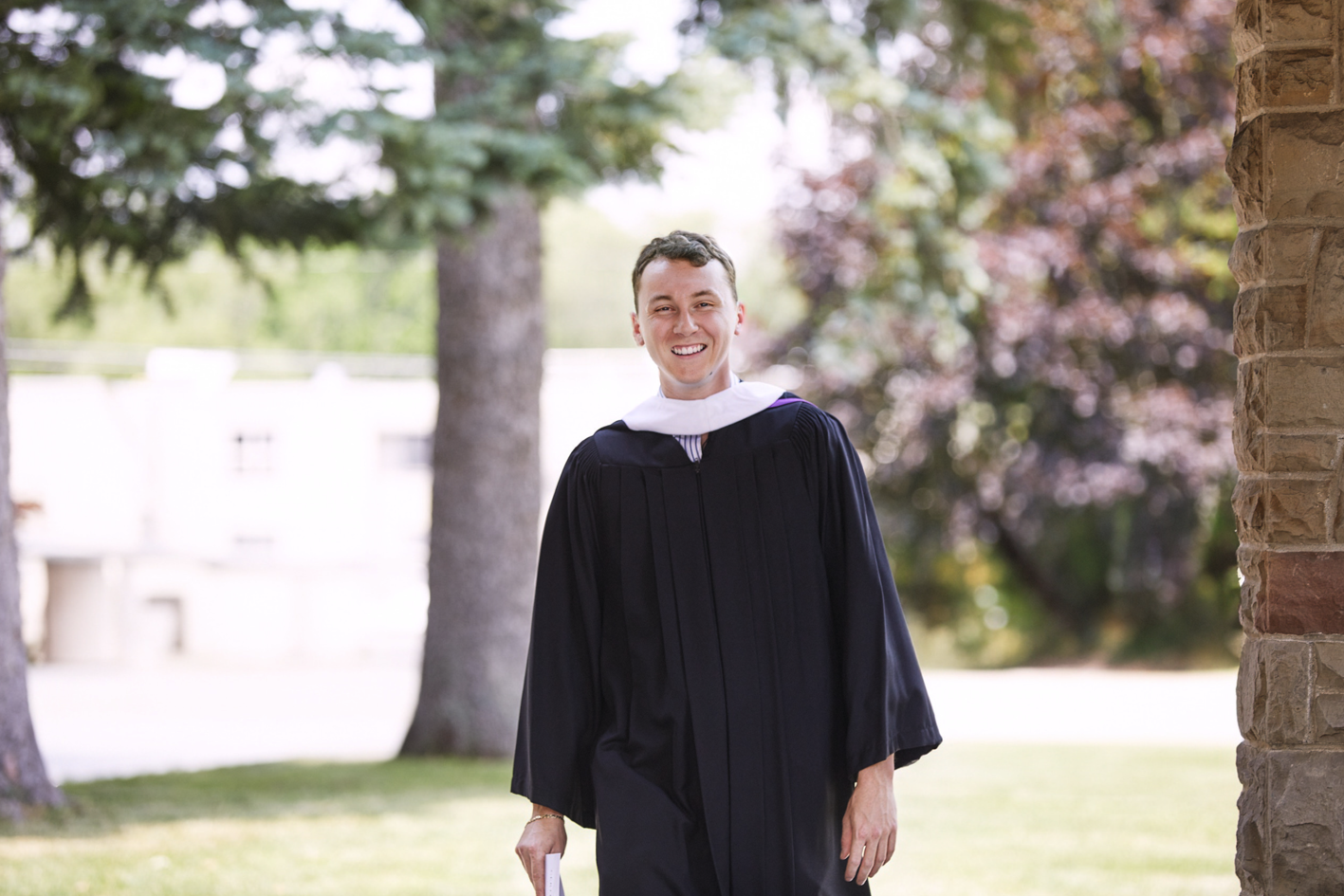 A smiling graduate in convocation gown